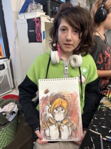 Young artist proudly displays a detailed anime-style drawing.