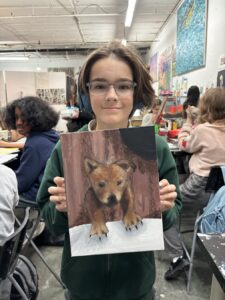 A young person holding a realistic painting of a fox.