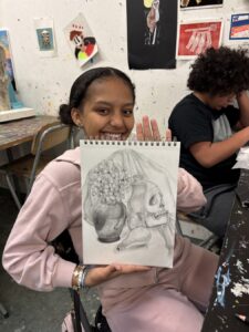 Girl proudly shows a detailed pencil drawing of a skull and brain.