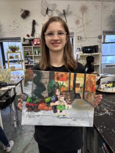 Young girl proudly displays her colorful diorama art project.