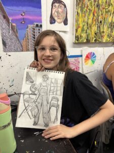 Smiling girl holding a detailed sketch in an art studio.