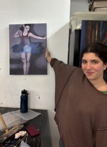 A person points at a ballerina poster on the wall.