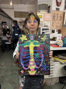 Person holding colorful artwork of a ribcage with vibrant designs.