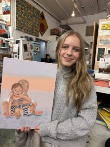 Young woman proudly holding an animal painting in a cozy studio.