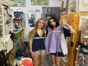 Two girls posing happily in a cozy, colorful room filled with decor.