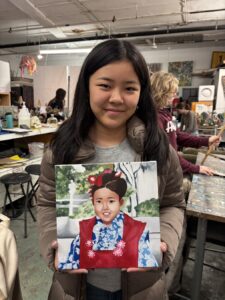 Young woman holding portrait of a girl in traditional clothing.