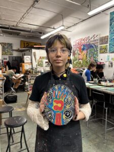 Person holding a colorful, circular art piece in an art studio.