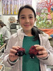 Smiling girl holding two small stuffed animals in a cozy indoor setting.
