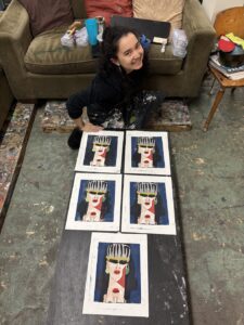 Person sitting on floor with five similar portraits arranged in front.