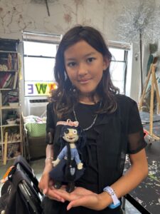 A young woman holding a small cartoon figurine indoors.