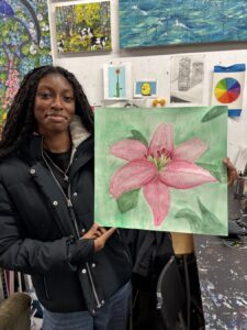Young woman proudly displays a painting of a pink flower.